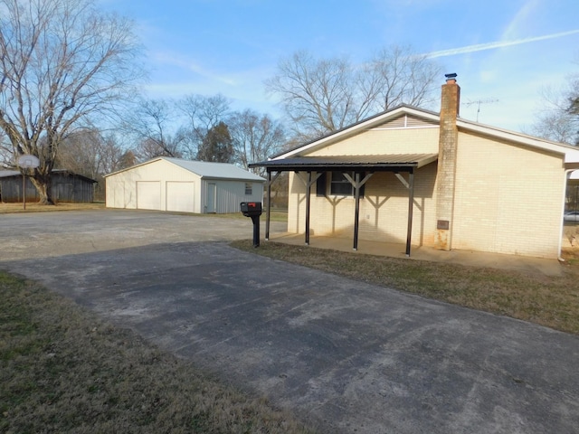 view of side of property with a garage, an outdoor structure, and a carport