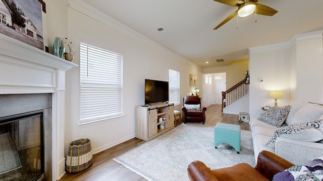 living room with hardwood / wood-style floors, ornamental molding, and ceiling fan