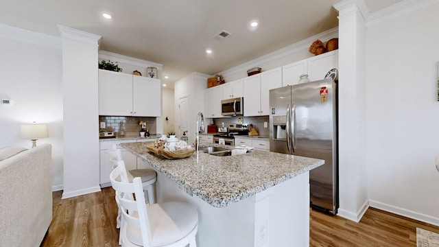 kitchen featuring white cabinetry, sink, a kitchen island with sink, light stone counters, and stainless steel appliances