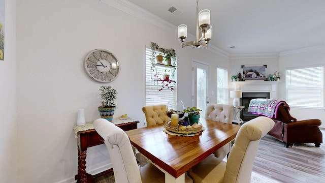 dining space featuring hardwood / wood-style floors, ornamental molding, a wealth of natural light, and a chandelier