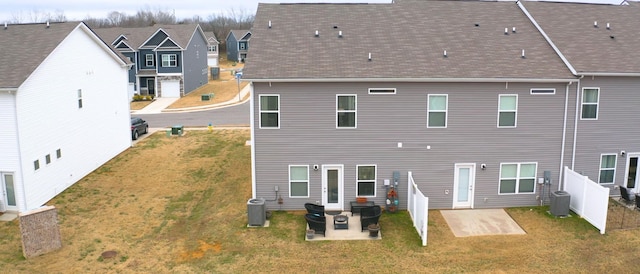 rear view of house with cooling unit, a lawn, and a patio