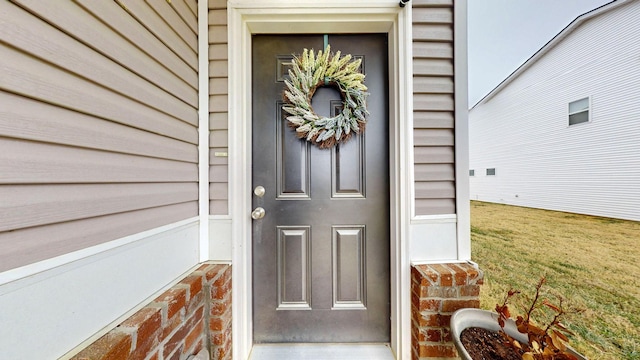 view of exterior entry featuring a lawn