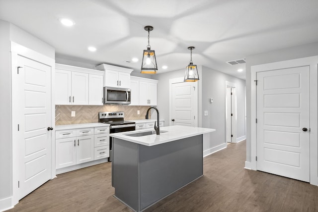 kitchen featuring sink, white cabinetry, pendant lighting, stainless steel appliances, and decorative backsplash