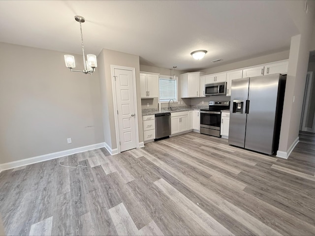 kitchen with white cabinetry, appliances with stainless steel finishes, decorative light fixtures, and light hardwood / wood-style flooring