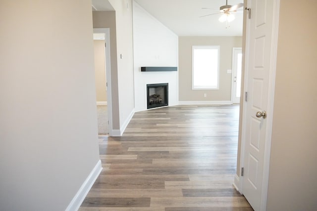 unfurnished living room featuring ceiling fan, a large fireplace, and light wood-type flooring