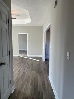 hallway with a tray ceiling and dark hardwood / wood-style flooring