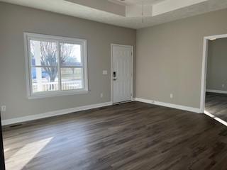 empty room with dark wood-type flooring and a raised ceiling