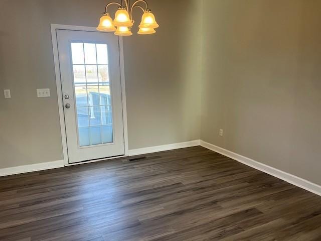 unfurnished dining area with dark wood-type flooring and a chandelier