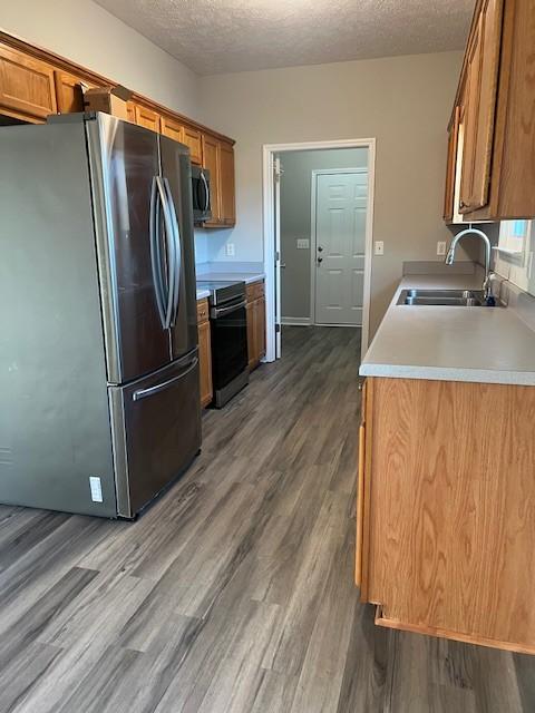 kitchen featuring dark hardwood / wood-style flooring, appliances with stainless steel finishes, sink, and a textured ceiling