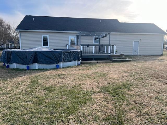 rear view of house with a swimming pool side deck and a yard