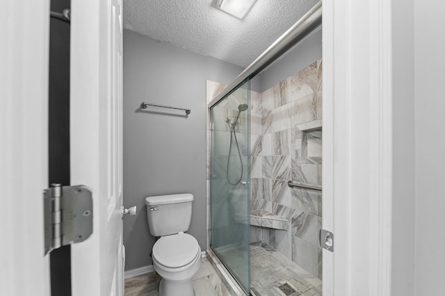 bathroom featuring walk in shower, toilet, and a textured ceiling