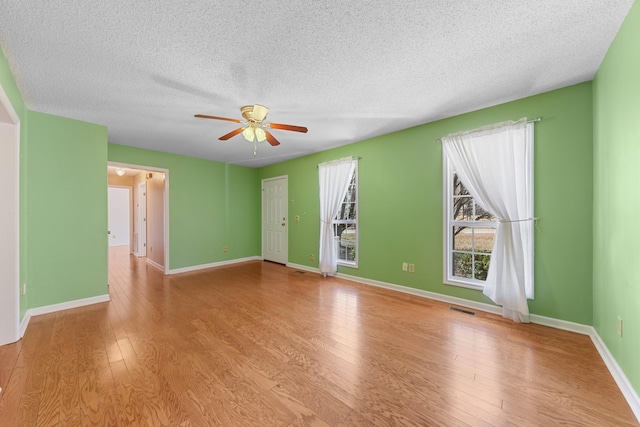 unfurnished room with ceiling fan, a textured ceiling, and light wood-type flooring