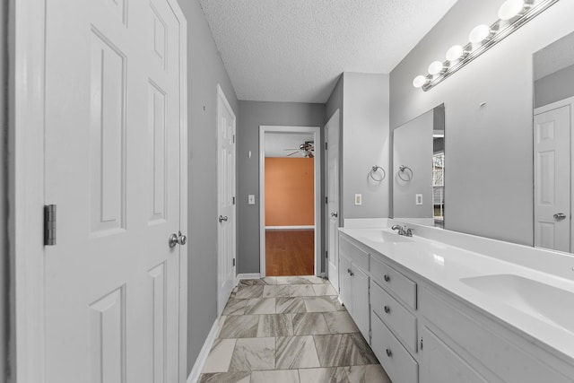 bathroom featuring vanity, ceiling fan, and a textured ceiling