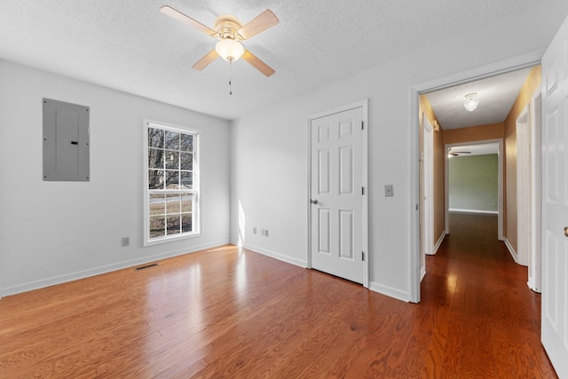 unfurnished room featuring ceiling fan, hardwood / wood-style floors, electric panel, and a textured ceiling