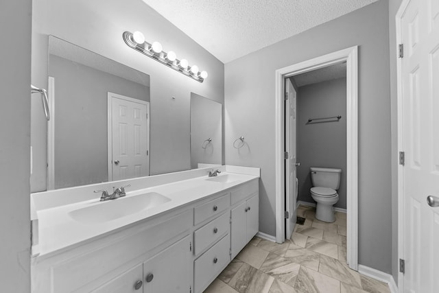 bathroom featuring vanity, toilet, and a textured ceiling