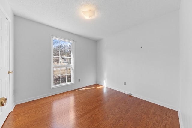 empty room with hardwood / wood-style floors and a textured ceiling