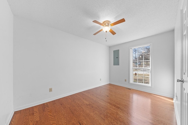 unfurnished room featuring a textured ceiling, light hardwood / wood-style flooring, electric panel, and ceiling fan