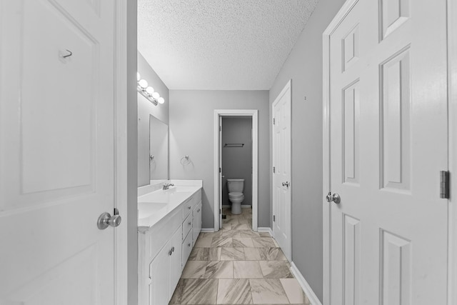 bathroom with vanity, toilet, and a textured ceiling