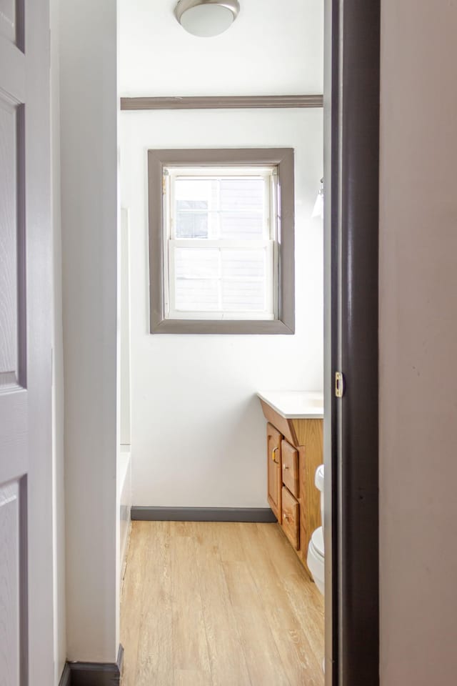 bathroom with a tub to relax in, toilet, crown molding, vanity, and hardwood / wood-style flooring