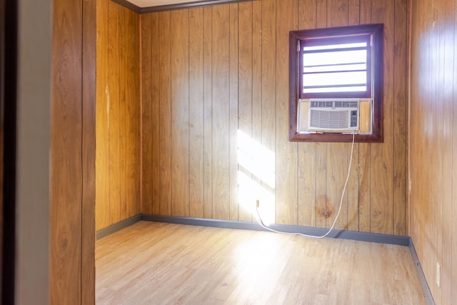 spare room with cooling unit, light hardwood / wood-style flooring, and wood walls