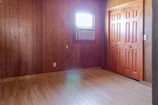 spare room with cooling unit, light hardwood / wood-style flooring, and wood walls