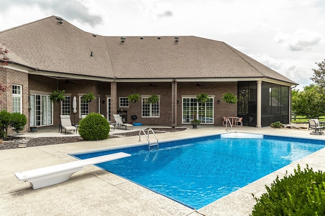 view of pool with a diving board, a patio area, and a sunroom