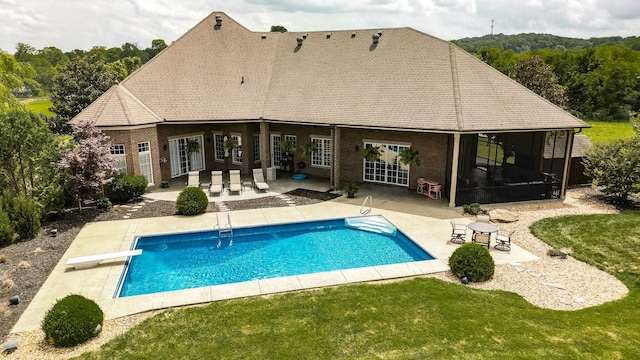 rear view of property featuring a sunroom, a patio area, and a lawn