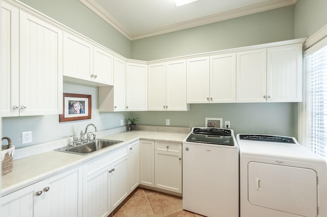 clothes washing area with sink, crown molding, light tile patterned floors, washing machine and dryer, and cabinets