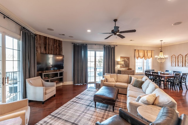 living room with ornamental molding, a healthy amount of sunlight, ceiling fan with notable chandelier, and dark hardwood / wood-style floors