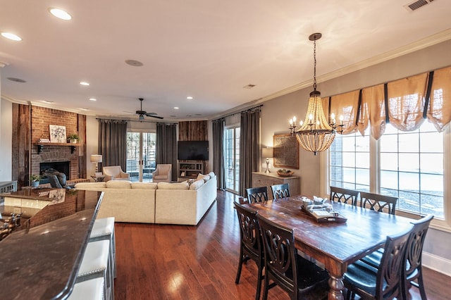 dining room featuring crown molding, a brick fireplace, dark wood-type flooring, and a wealth of natural light