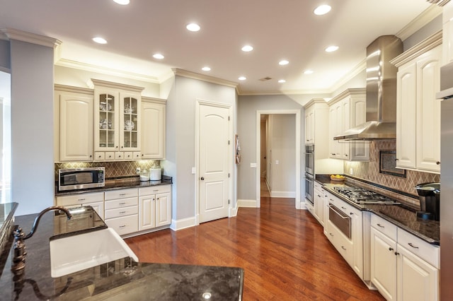 kitchen with sink, decorative backsplash, stainless steel appliances, and wall chimney exhaust hood