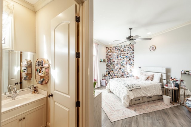 bedroom with crown molding, ceiling fan, sink, and hardwood / wood-style floors