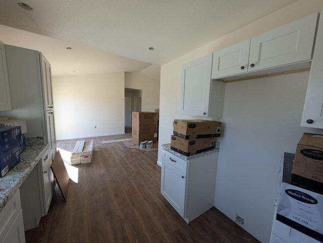 kitchen with vaulted ceiling, dark wood-style floors, white cabinetry, and light stone countertops