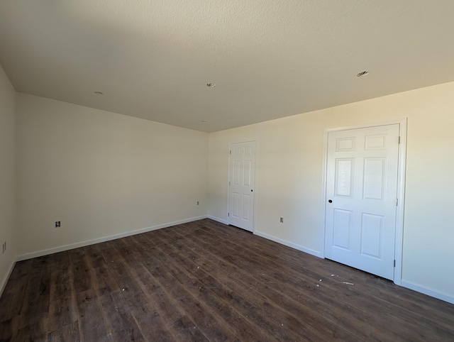 unfurnished bedroom with baseboards and dark wood finished floors