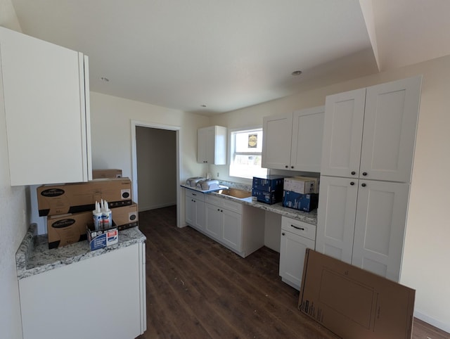 kitchen with dark wood-type flooring, light stone countertops, and white cabinets