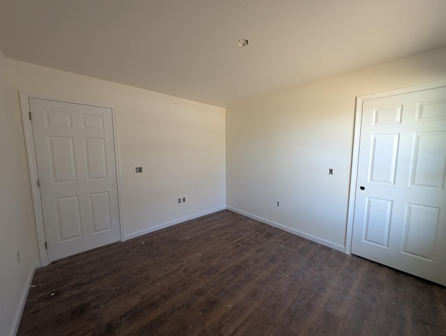 empty room with baseboards and dark wood-style flooring