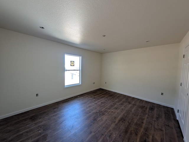 unfurnished room with a textured ceiling, dark wood finished floors, and baseboards