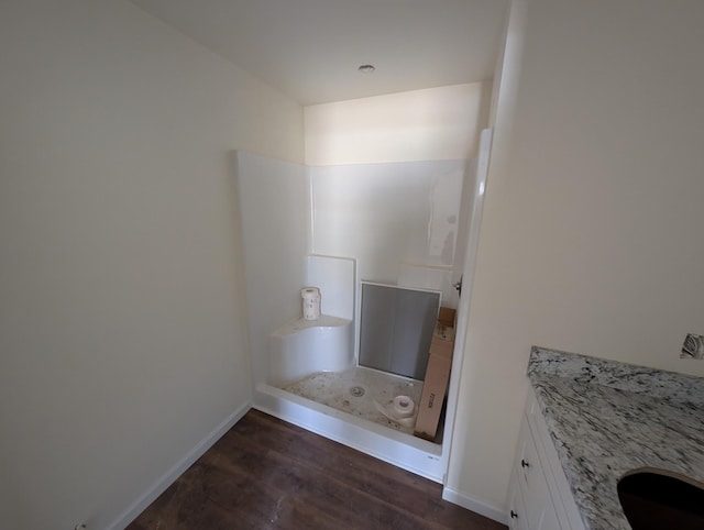 bathroom with walk in shower, baseboards, and wood finished floors