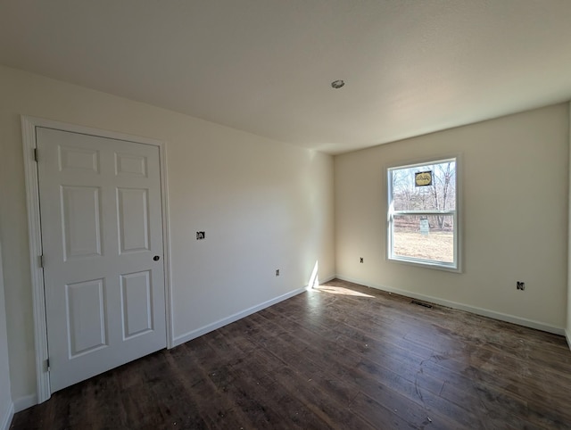 unfurnished room featuring dark wood-style floors and baseboards