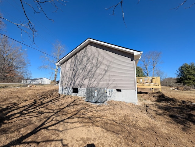 view of side of home with crawl space, a deck, and central air condition unit