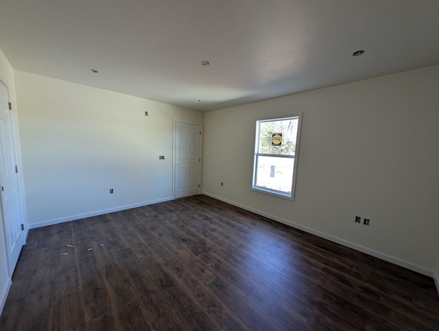 unfurnished room featuring baseboards and dark wood-style flooring