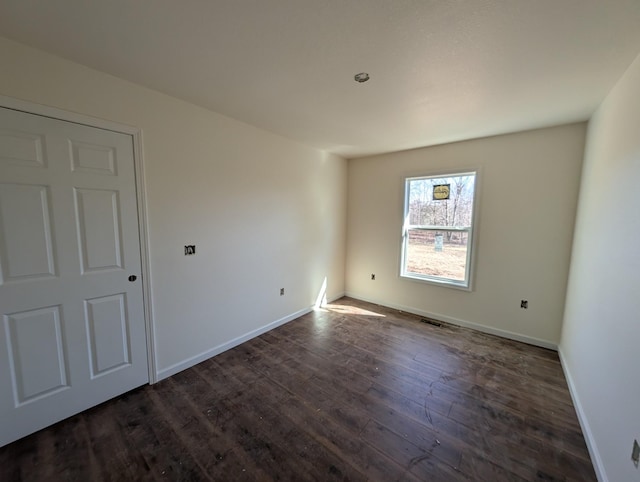 unfurnished room with dark wood-style flooring and baseboards