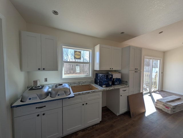 kitchen featuring a sink, dark wood finished floors, white cabinetry, and baseboards