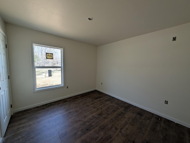 unfurnished room with dark wood-style flooring and baseboards