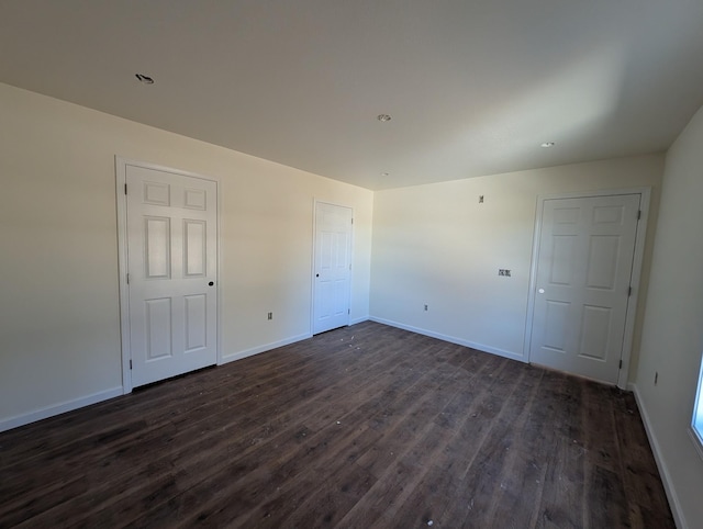 unfurnished bedroom featuring baseboards, dark wood-style flooring, and recessed lighting