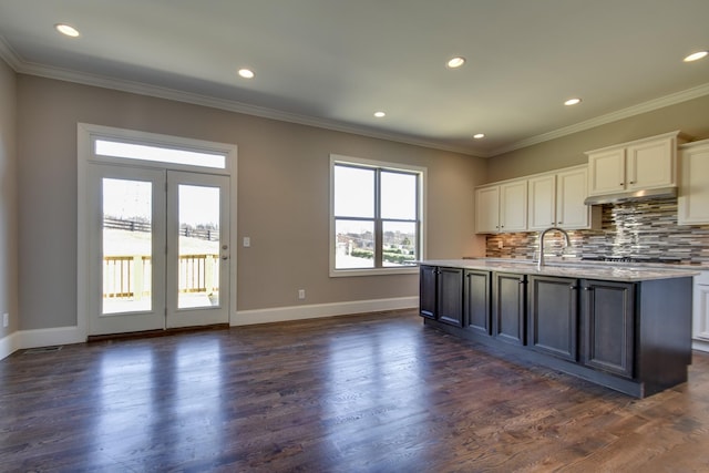 kitchen featuring dark hardwood / wood-style flooring, crown molding, a kitchen island with sink, and white cabinets