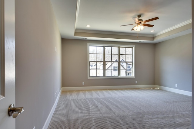 carpeted empty room featuring ornamental molding, ceiling fan, and a tray ceiling