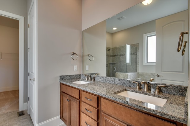 bathroom with a shower with door, vanity, and tile patterned flooring