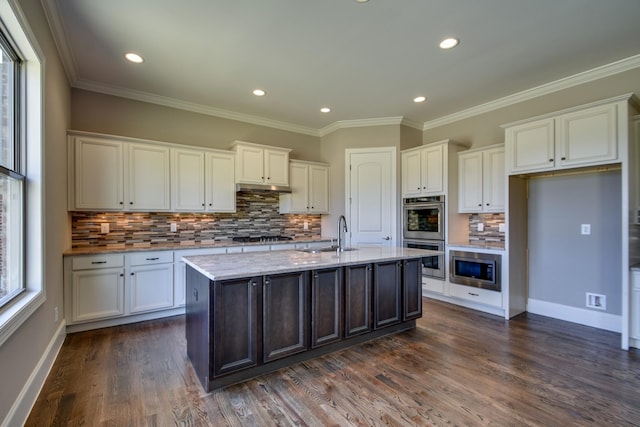 kitchen with stainless steel appliances, white cabinetry, a kitchen island with sink, and ornamental molding