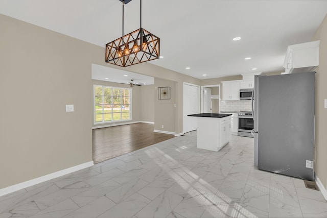 kitchen featuring tasteful backsplash, decorative light fixtures, appliances with stainless steel finishes, a kitchen island, and white cabinets